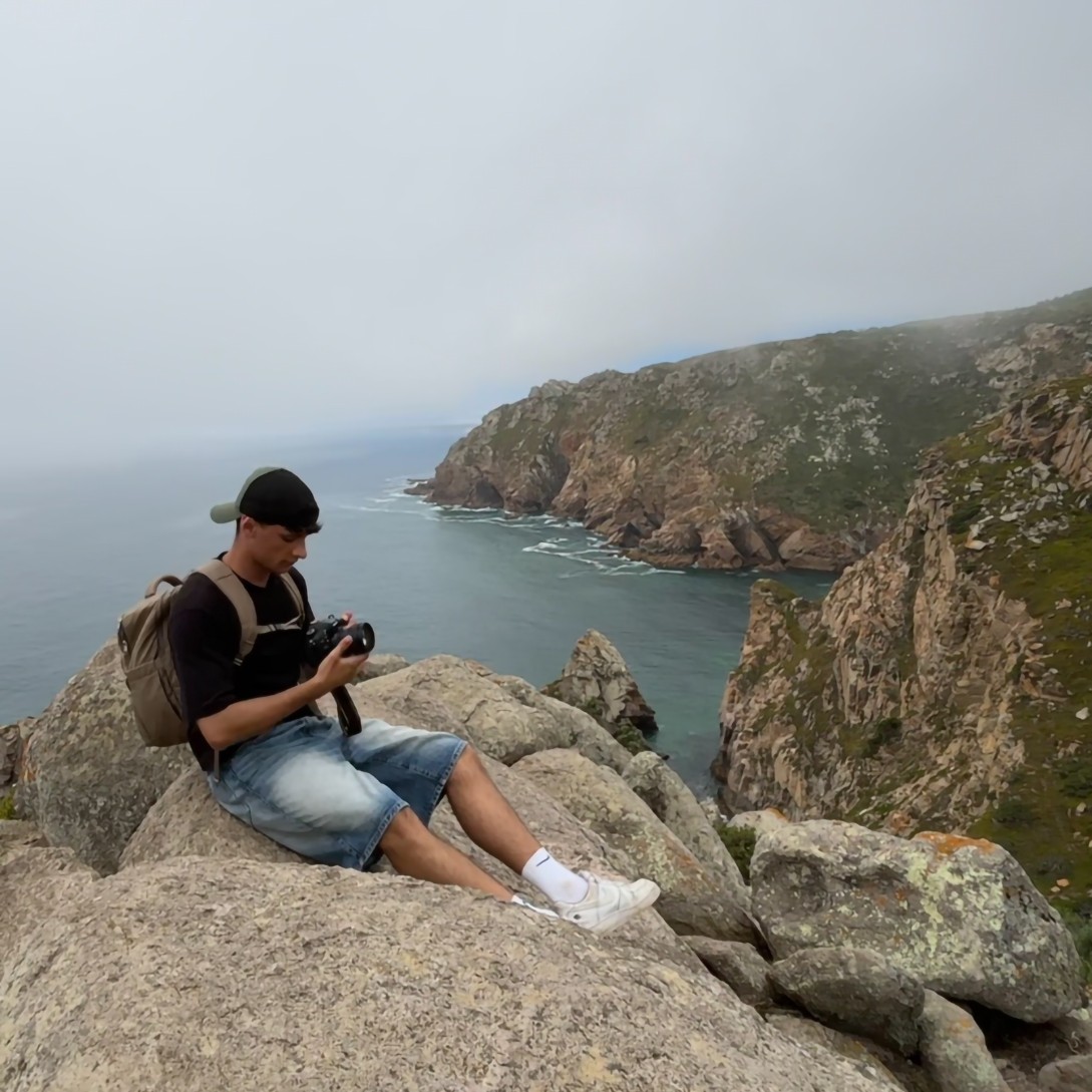 Antonio Bua seduto su una scogliera mentre controlla la macchina fotografica